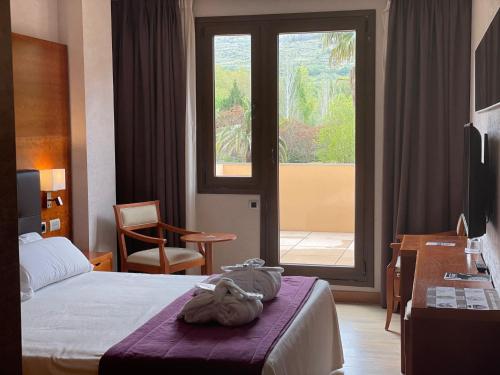 a hotel room with a bed and a large window at Hotel Balneario Valle del Jerte in Valdastillas