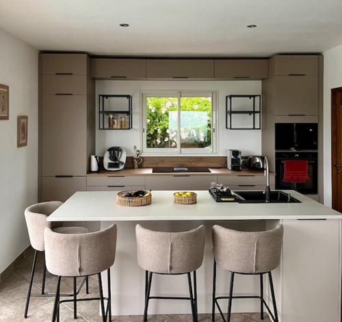 a kitchen with a island with chairs and a counter top at Villa Standing - Piscine et Vue Mer in Alata