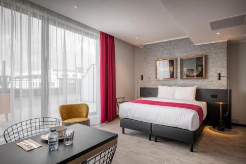 a hotel room with a bed and a desk and a room at Hotel Jamingo in Antwerp