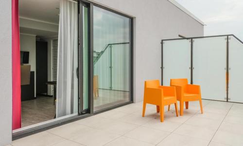 a dining room with orange chairs and windows at Hotel Jamingo in Antwerp