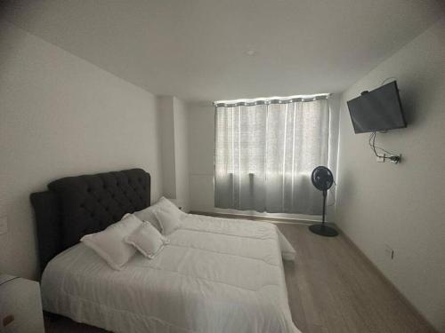 um quarto branco com uma cama e uma janela em Atractivo Apartaestudio Conj Res em Floridablanca