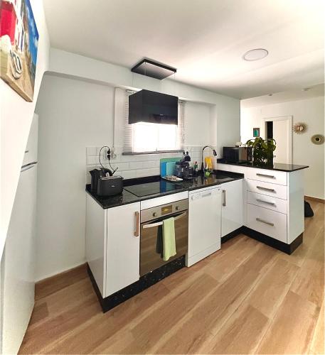 a kitchen with white cabinets and black counter tops at Casa San Miguel in Estepona