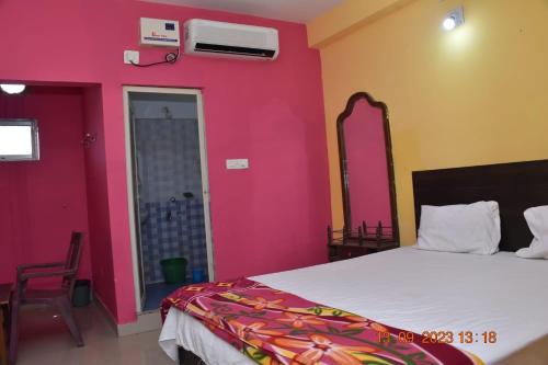 um quarto com uma cama e uma parede rosa em HOTEL K.K PALACE em Puri