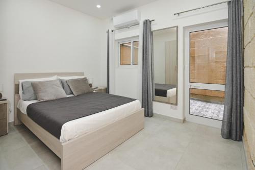 een slaapkamer met een bed en een groot raam bij Widnet il-Bahar in Marsalforn