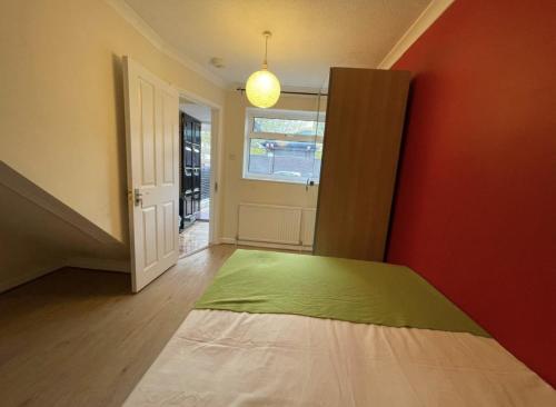 a bedroom with a green bed and a red wall at Cozy Urban Retreat: Shared Flat Living in the Heart of E14 in London