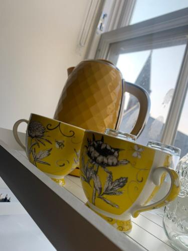 two cups sitting on a shelf next to a window at STAG & THISTLE HOTEL AND RESTAURANT in Fraserburgh