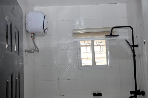 a window in a white tiled bathroom with a shower at FANZMA ApArtment in Aso