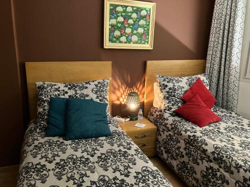 a bedroom with two beds with pillows and a lamp at The Twins beds in Nouaseur