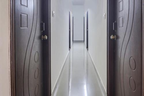 a hallway with wooden doors and a long corridor at Super OYO Collection O Hotel Sbr Luxury Rooms in Hyderabad