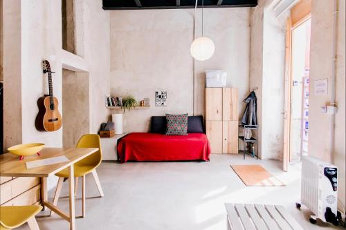 ein Wohnzimmer mit einem roten Bett und einer Gitarre in der Unterkunft Estudio Loft en el centro de Madrid reformado en enero 2024 in Madrid