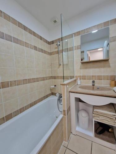 une salle de bain avec une baignoire, un lavabo et un miroir dans l'établissement Maison cosy 4-6 personnes - Village Pierre & Vacances, à Grospierres