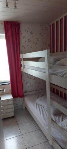 ミッデルケルケにあるDezaligheidのベッドルーム1室(赤いカーテン付きの二段ベッド2組付)