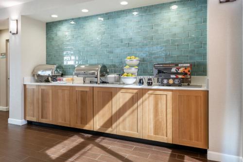 a kitchen with wooden cabinets and a green wall at Surf and Sand Fernandina Beach at Amelia Island, an Ascend Collection Hotel in Fernandina Beach