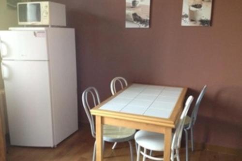 uma cozinha com uma mesa com cadeiras e um frigorífico branco em Cozy apartment with balcony and nice mountain view em Annecy