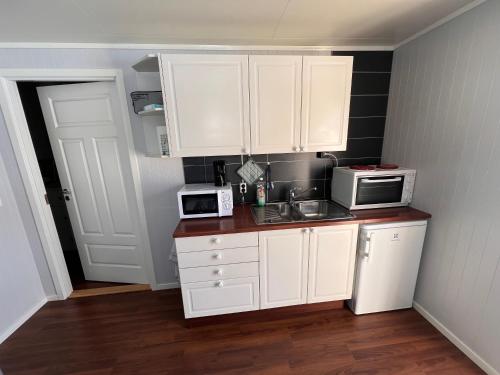 cocina con armarios blancos, fregadero y microondas en Lofoten booking en Leknes