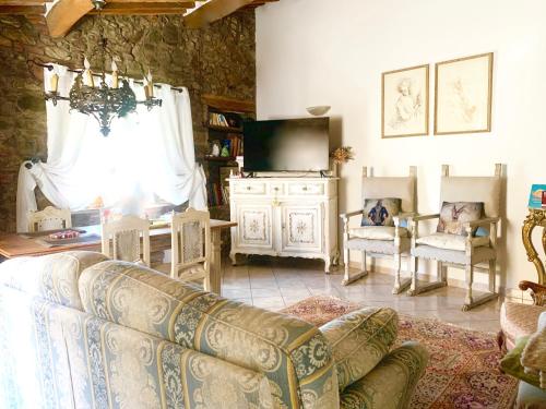 ein Wohnzimmer mit einem Sofa und einem TV in der Unterkunft Casa Malù Suvereto Antica Dimora with two bedrooms in Suvereto