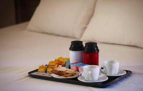 a tray of breakfast food and two cups on a bed at Motel Status (only adults) in Pato Branco