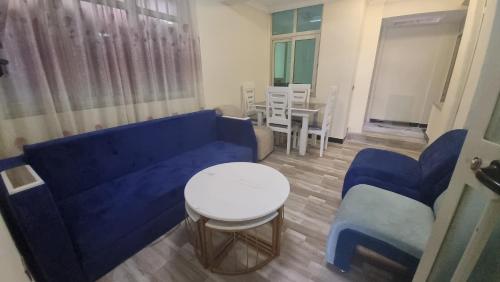 sala de estar con sofá azul, mesa y sillas en Getu furnished apartments at CMC en Addis Abeba