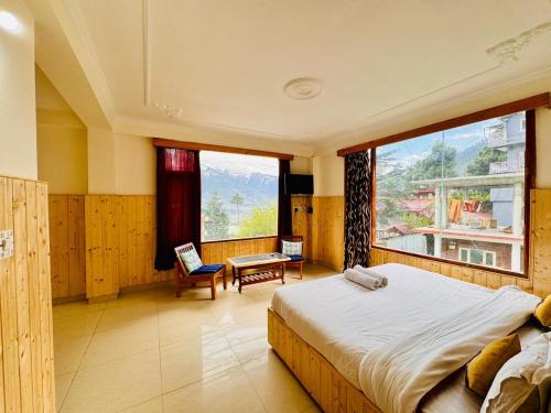 ein Schlafzimmer mit einem Bett und einem großen Fenster in der Unterkunft Hotel Suraj Retreat inn in Manali