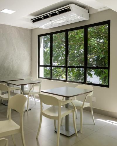 a classroom with tables and chairs and a large window at Ilha Porchat Hotel in São Vicente