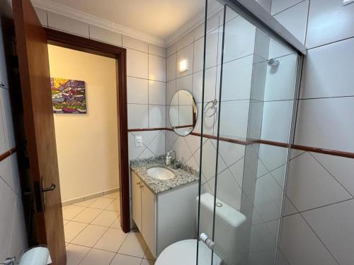 uma casa de banho com um WC, um lavatório e um espelho. em Apartamento Canto Do Forte - Praia Grande Top na Praia Grande