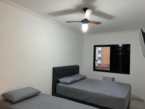 a bedroom with two beds and a ceiling fan at Apartamento Canto Do Forte - Praia Grande Top in Praia Grande