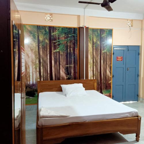a bedroom with a bed with a painting of trees at Aranya Darshan in Lataguri