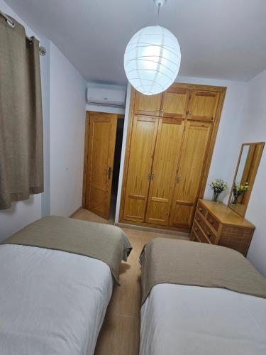 um quarto com 2 camas e um lustre em Apartamento El Ingenio em Nerja