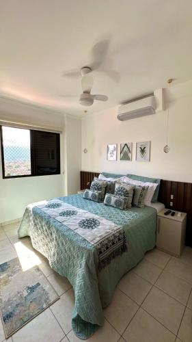 a bedroom with a bed with a blue comforter at Apto Lindo e Completo Beira Mar - Vila Caiçara in Solemar