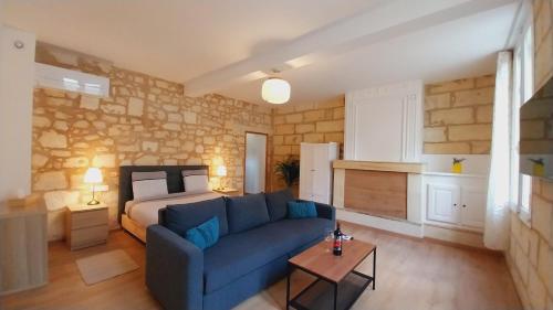 - un salon avec un canapé bleu et un lit dans l'établissement Hôtes de Saint Emilion II, à Saint-Émilion