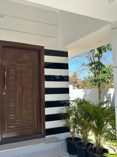a wooden door on a house with potted plants at Sapphire Stayss in Yelagiri