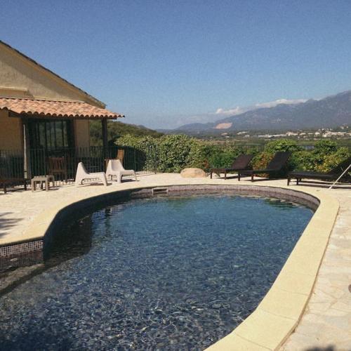 une grande piscine avec des chaises et une maison dans l'établissement Grande villa familiale vue mer près de Palombaggia, à Porto-Vecchio