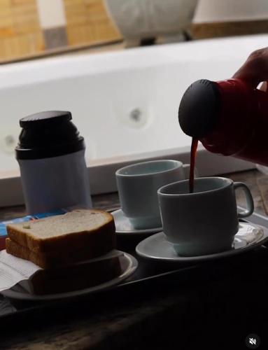 una persona está vertiendo salsa en una taza de café en Motel Status (only adults), en Pato Branco
