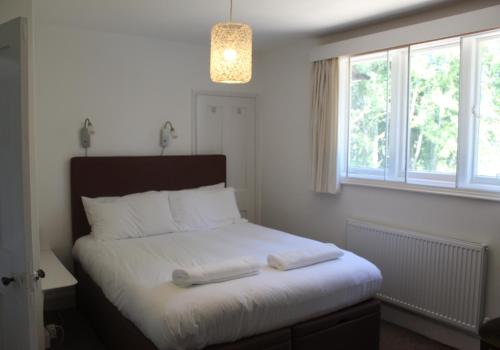 a bedroom with a bed with white sheets and a window at Cosy Family Cottage, Semi Rural Retreat - Dogs Welcome! Nearby Countryside, Beaches & Goodwood in Eartham