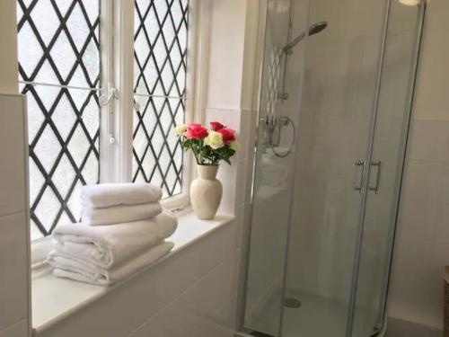 un baño con un jarrón con flores en el alféizar de la ventana en Cosy Family Cottage, Semi Rural Retreat - Dogs Welcome! Nearby Countryside, Beaches & Goodwood en Eartham