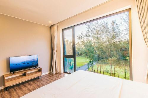 a bedroom with a tv and a large window at Sea Villa - FLC Sam Son in Sầm Sơn