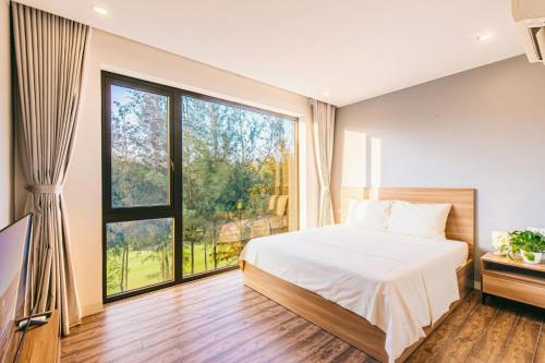 a bedroom with a bed and a large window at Sea Villa - FLC Sam Son in Sầm Sơn