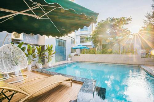 a swimming pool with chairs and an umbrella at Sea Villa - FLC Sam Son in Sầm Sơn
