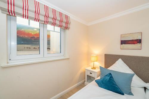 um quarto com uma janela e uma cama com almofadas azuis em Hannah em Westerland