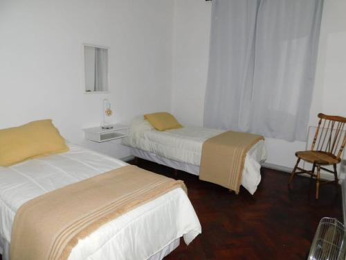um quarto de hotel com duas camas e uma cadeira em Departamento calle Espejo em Mendoza