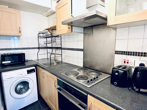 a kitchen with a stove and a washing machine at Hoxton Studios by DC London Rooms in London