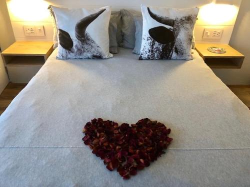 a heart shaped pile of rose petals on a bed at Small Bay Beach Suites in Cape Town