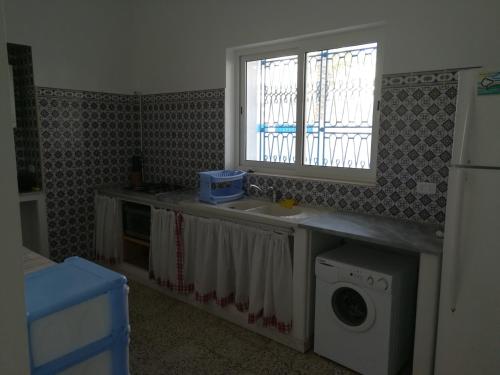 a kitchen with a sink and a washing machine at L'espadon de Mahdia Maison avec petit jardin in Mahdia