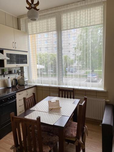 a kitchen with a table and chairs and a large window at Butų nuoma Šilutėje in Šilutė