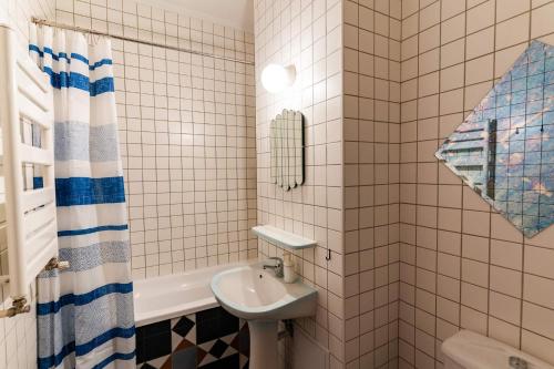 a white tiled bathroom with a sink and a tub at Rezident in Bucharest