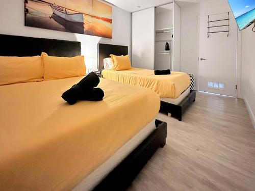 two beds in a room with yellow sheets at Vacay Spot experience Luna Sky! 65" TV BAR, BBQ, SHOWER massage jets, music, go to FL Keys in Homestead