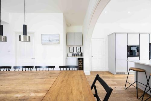 a kitchen and dining room with a wooden table and chairs at The Lymington Hub Slps 13 hot tub/chef/spa in Lymington