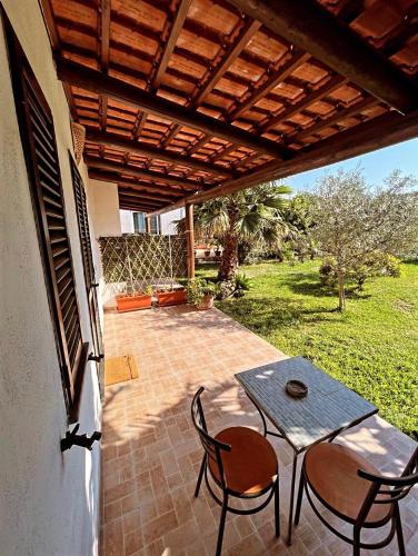 een patio met een tafel en stoelen onder een houten dak bij Case vacanze le Buganville in Ischia