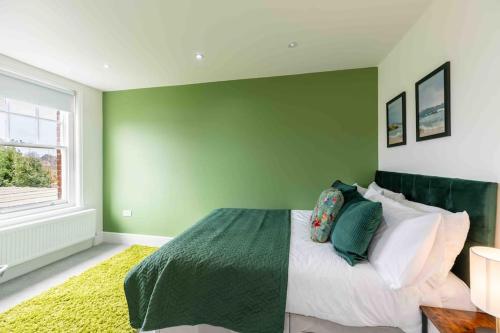 a bedroom with green walls and a bed with pillows at The Lymington Hub Slps 13 hot tub/chef/spa in Lymington
