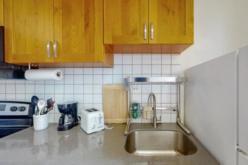 a kitchen with a sink and wooden cabinets and a counter top at Waikiki Banyan 913 in Honolulu